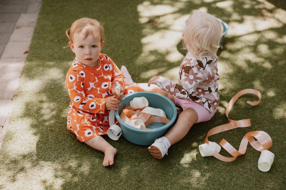Twee kleintjies wat rustig saam op die gras speel