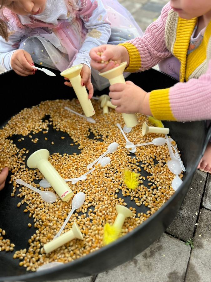Klein handjies wat met mielies en tregters speel